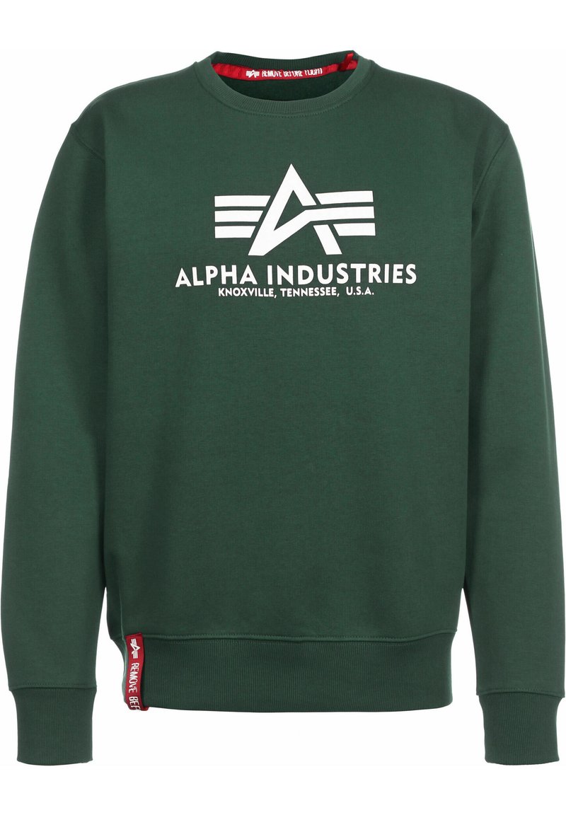 Sudadera verde oscura con cuello redondo, que presenta un logo impreso en blanco y el texto "ALPHA INDUSTRIES" en el frente. Etiqueta de acento roja en el dobladillo.