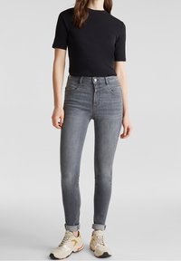 Höga grå denimjeans med slim fit, lätt stretch, subtilt blekt mönster och uppvikta fållar. Matchas med en svart t-shirt med kort ärm.