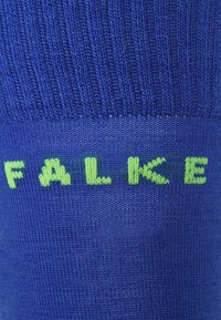 Calzino blu a maglia con lettering verde "FALKE". Texture liscia con struttura a costine nella parte superiore, adatto per l'uso quotidiano.