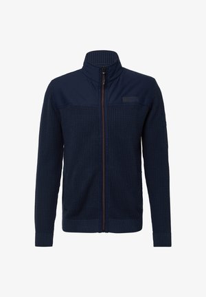 Tumesinine zip-up jope, millel on tekstuuriga kudum kehast, siledast kangast ülemine osa, soonikkoes krae ja mansetid, millel on erinevat värvi tõmblukk ja märgi detail.