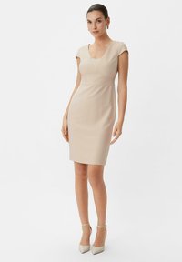 Beiges tailliertes Kleid mit V-Ausschnitt, kurzen Ärmeln und horizontalen Nahtdetails in der Taille. Glatte Textur, Bleistiftsilhouette.