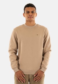 Sudadera beige con cuello redondo y puños acanalados. Presenta un pequeño logotipo en el pecho. Confeccionada con una tela texturizada y suave.