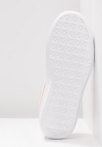Semelle blanche de sneaker avec motif de bande de roulement en forme d'étoile et logo Puma au talon, vue de dessous sur fond blanc.