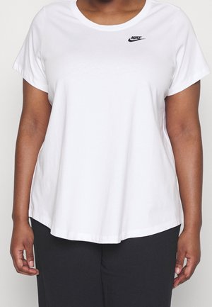 Personne portant un t-shirt Nike blanc uni à manches courtes avec un petit logo noir sur le haut gauche de la poitrine, assorti à un pantalon noir.