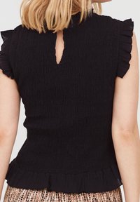 Top nero con un design smock tessuto, maniche a cappuccio con volant, un'apertura a chiave sul retro e un orlo arricciato.