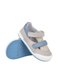Zapatos infantiles en gris y azul claro con cintas de velcro, materiales de cuero y ante, forma curva y suela de goma texturizada.