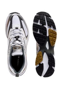 Sneaker Lacoste con parte superiore in rete bianca, accenti argento, suola in gomma nera e dorata e lacci piatti. Presentano un design a punta rotonda.