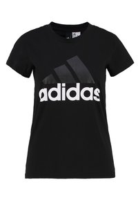 Černé bavlněné tričko s kulatým výstřihem, na přední straně má velké bílé logo "adidas" a tři černé diagonální pruhy.