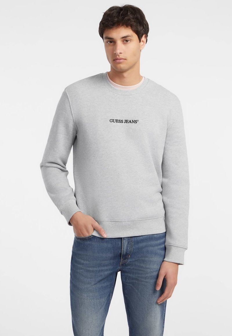 Sudadera gris hecha de una mezcla de algodón, con cuello redondo y puños de canalé, con "GUESS JEANS" bordado en negro en el pecho.