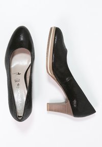 Svarta högklackade pumps med texturerad ovandel, rund tå och staplad träklack. Slät insida med en subtil glittrande finish.