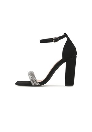Czarna sandałka na wysokim słupku, z paskiem wokół kostki zapinanym na sprzączkę oraz przednim paskiem ozdobionym małymi kryształkami.