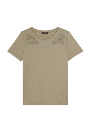 Camiseta beige de manga corta con escote redondo, patrones florales calados en los hombros y pequeño texto de marca en cursiva en la parte inferior derecha.
