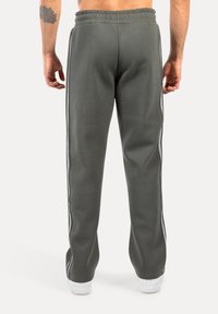 Graue Sporthosen aus weichem Material, mit einer schmalen Passform, elastischem Bund und kontrastierenden weißen Seitenstreifen.