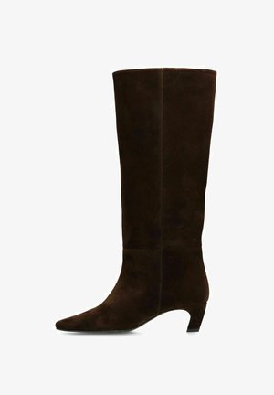 Botte marron en daim montant jusqu'au genou avec un bout pointu et un talon bas incliné. Texture lisse et détails de coutures minimaux visibles sur le côté.