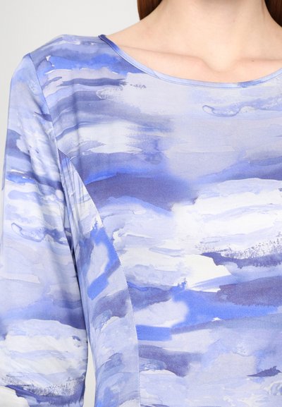 Blue abstract-patterned top made of smooth fabric, featuring a boat neckline and long sleeves. Design includes blended light and dark blue hues.