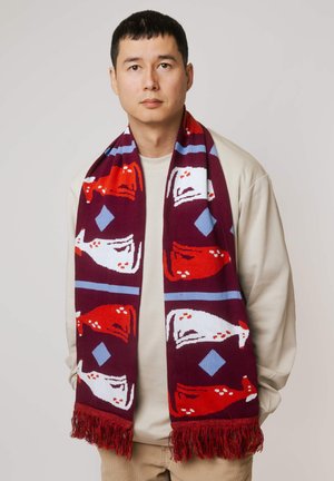 Dzianinowy szalik o bordowym tle z niebieskimi i czerwonymi wzorami, zakończony frędzlami na końcach oraz geometrycznymi akcentami na całej powierzchni.