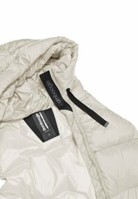 Licht beige pufferjack met capuchon, met een gestikt ontwerp, ritsluiting en een merklabel aan de binnenkant. Glad, reflecterend materiaal.
