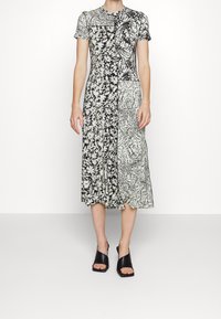 Sukienka midi z połączeniem czarno-białych wzorów kwiatowych i abstrakcyjnych, z krótkimi rękawami, okrągłym dekoltem i rozkloszowanym dołem.