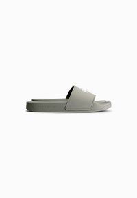 Green rubber slide sandal with a wide strap featuring white text, lightweight design, and textured footbed for comfort.
