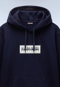 Felpa con cappuccio blu navy dotata di tasca a marsupio frontale, con un logo rettangolare bianco "NAPAPIJRI geographic" sul petto.
