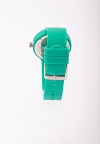 Un reloj de silicona turquesa con una esfera redonda, hardware plateado y una correa texturizada que presenta agujeros para ajuste.