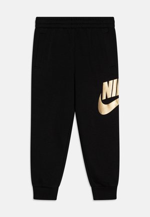 Pantalones deportivos negros hechos de tela suave, con una cintura elástica, bolsillos laterales y un gran logo dorado de Nike en la pierna izquierda.