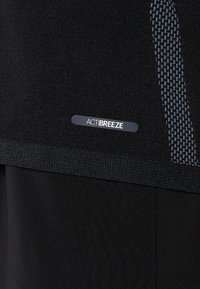 Black athletic shirt featuring a textured pattern on the side, with a smooth fabric finish. Label reads "ACTIBREEZE."