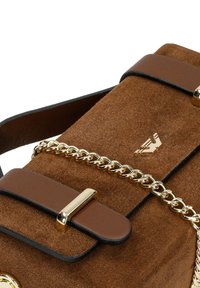 Sac à main en daim marron avec bandoulière chaîne dorée, détails en cuir marron avec boucle, et logo doré sur le rabat avant.
