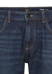 Dunkelblaue Jeans aus Denim mit lockerer Passform, orangefarbigen Nähten, einem vorderen Knopfverschluss und klassischem Fünf-Taschen-Design.