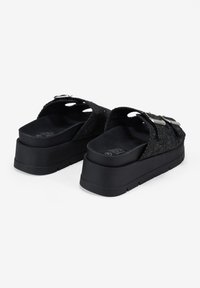 Black platform sandals with textured fabric upper, two buckle accents, and a molded footbed; thick rubber sole with tread pattern.