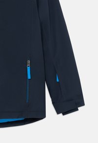 Marineblauer wasserdichter Jacke mit kontrastierenden blauen Reißverschlüssen und Akzenten, strukturiertem Design und verstellbaren Ärmeln.