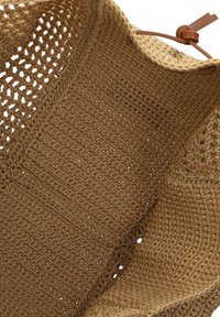 Bruine gehaakte tas met een gestructureerd patroon en open geweven delen, met een leren schouderband en een grote, ruime binnenkant.