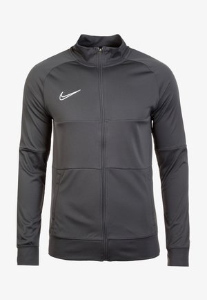 Veste de sport noire Nike zippée avec manches longues et col montant, arborant un logo Nike swoosh blanc sur la poitrine.