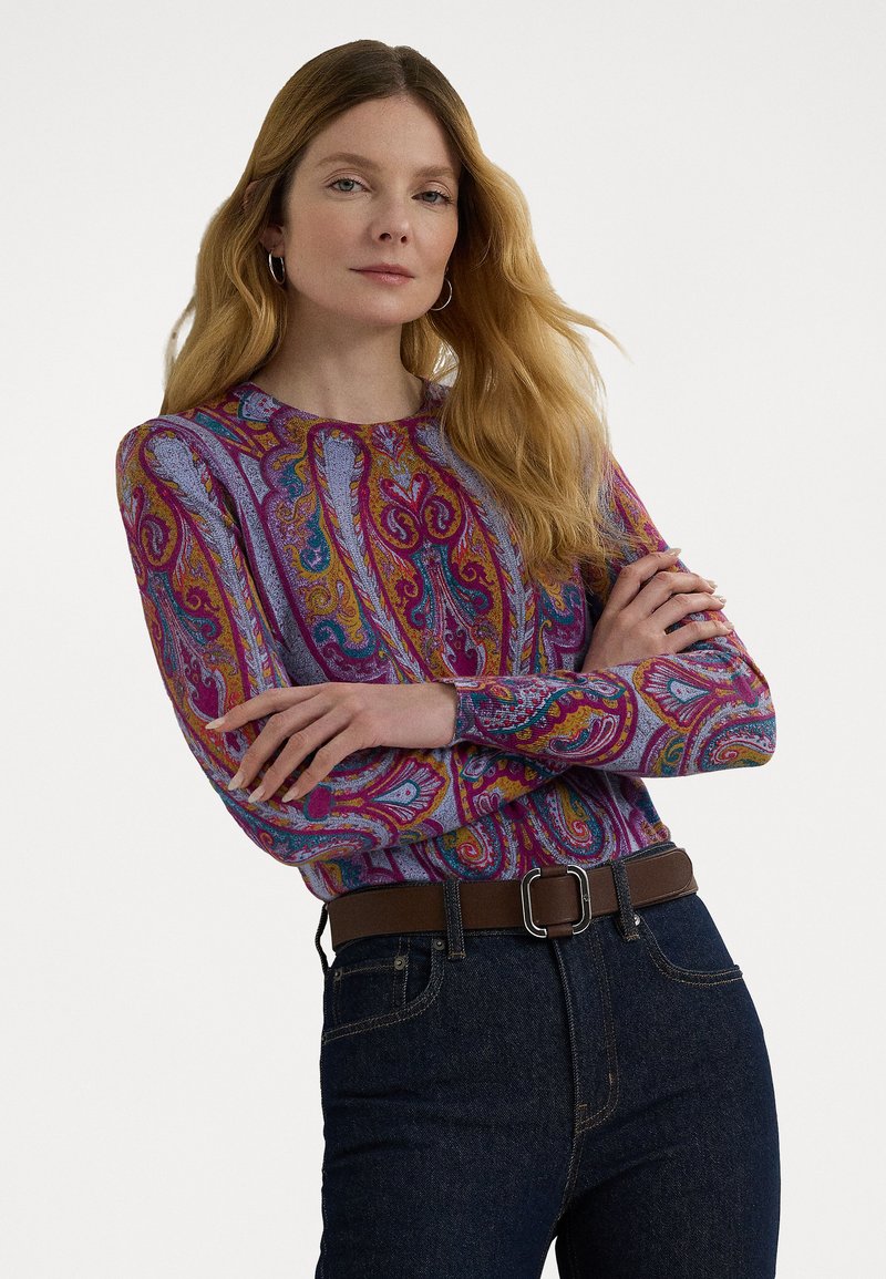 Hosszú ujjú, színes paisley mintás pulóver, puha anyagból készült, sötétkék farmernadrággal és ezüstcsatos barna övvel párosítva.