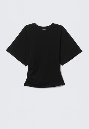 T-shirt noir à manches courtes avec col rond et coupe légèrement oversize, présenté sur un fond gris clair.