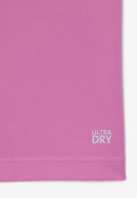 Tela texturizada rosa con dobladillo cosido y texto blanco "ULTRA DRY" impreso cerca del borde inferior en el lado derecho.