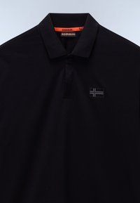 Crna pamučna polo majica s oštrim kragnom, koja ima narančasti tag i mali sivi zastavasti logo na lijevoj strani prsnog područja.