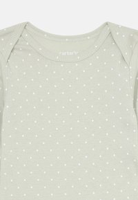 Un body pour bébé vert clair avec un motif à pois blancs, un col rond et des manches longues, fabriqué en coton doux.
