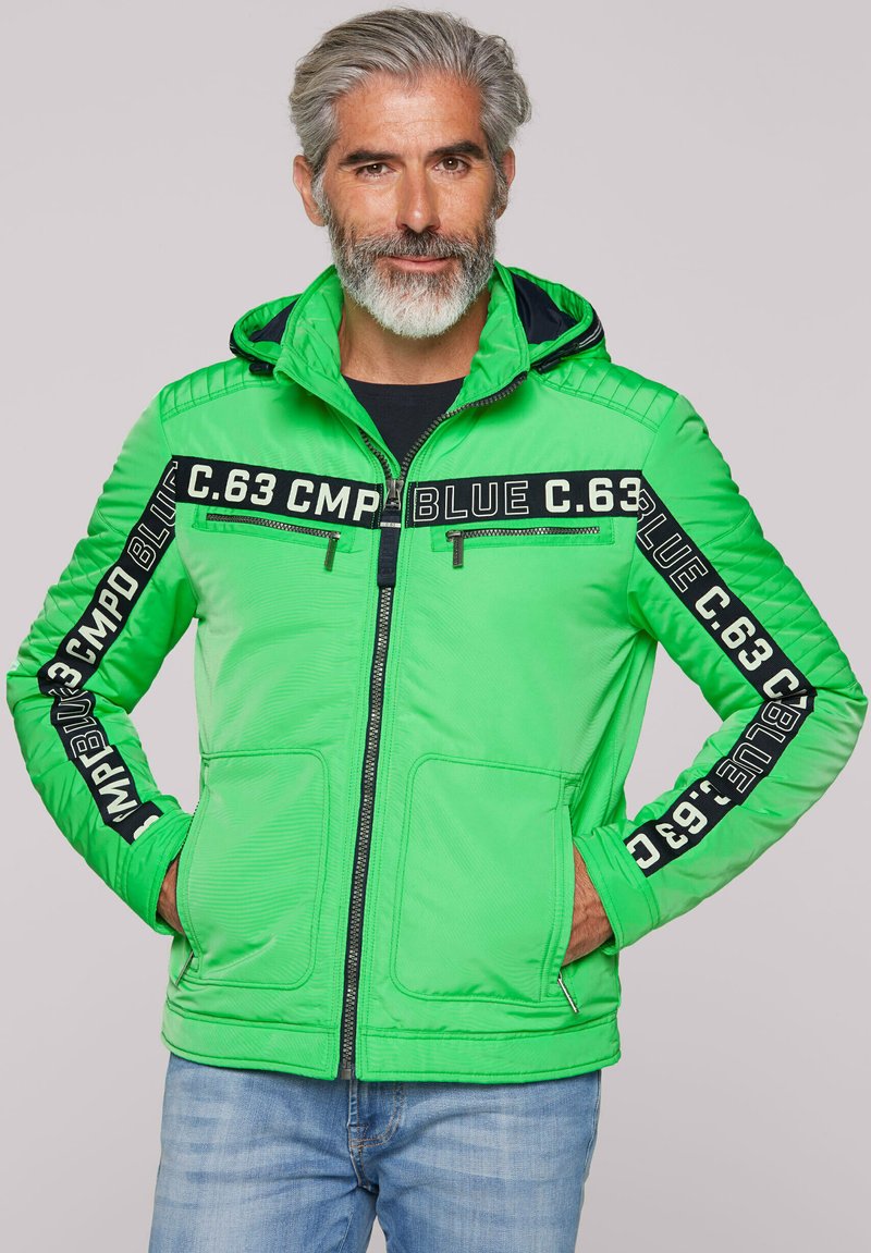 Grüne gepolsterte Jacke mit Kapuze, ausgestattet mit schwarzen Textakzenten, zwei Fronttaschen und einem Reißverschluss. Der Stoff wirkt glatt und strukturiert.