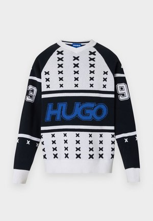 Pull en tricot noir et blanc avec des motifs géométriques, arborant un logo bleu vif et des accents numérotés (3 et 9) sur les manches. Design en V.