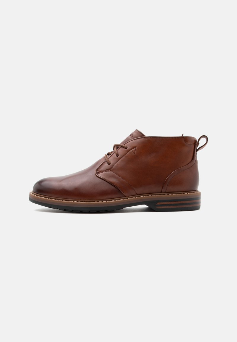 Bottine en cuir marron avec laçage à l'avant, talon bas et languette à l'arrière, vue de profil côté extérieur sur un fond uni.
