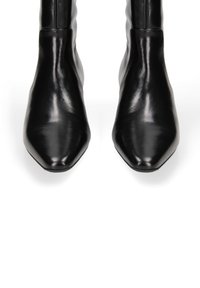 Stivali ankle in pelle nera con punta appuntita e finitura liscia, caratterizzati da un design elegante e aderente senza accessori visibili.