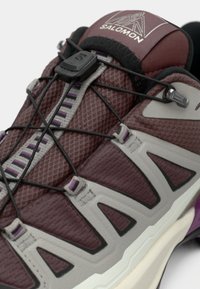 Πεζοπορικό παπούτσι Salomon με πάνω μέρος από δίχτυ μαρονού και γκρι, με κλειστό σύστημα κορδονιών, υφασμένα διακοσμητικά και λαστιχένια σόλα.