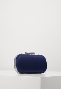 Siniset clutch-laukku, jossa on sileä pinta, pyöristetty muoto, metallilukko ja hopeanväriset reunat ja yläosa.