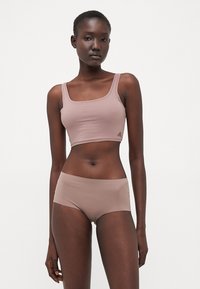 Light brown sports crop top and briefs with a smooth texture. The crop top features a square neckline and a small logo on the side.