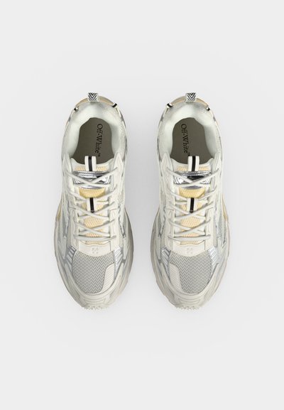 Paire de baskets Off-White blanches et beiges avec des détails en mesh et cuir, vues de dessus sur un fond blanc uni.