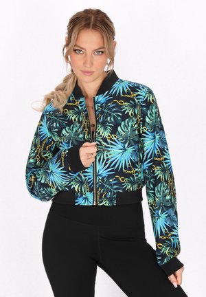 Korte bomberjack met een levendige tropische bladerenprint in tinten blauw en groen, voorzien van gouden kettingaccenten en zwarte ribgebreide afwerking.