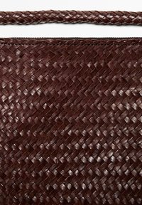 Borsa marrone intrecciata in pelle con motivo a trama. Presenta una maniglia robusta intrecciata e una chiusura con zip lungo la parte superiore.