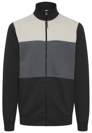 Chaqueta con cremallera que presenta un alto cuello con un diseño de bloques de color en blanco, gris y negro. Fabricada con un material suave y elástico.