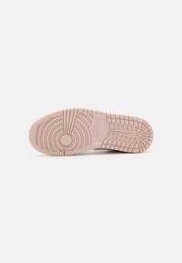 Semelle extérieure de basket Nike en caoutchouc rose doux, présentant des motifs de traction circulaires et linéaires, avec un détail logo central et une surface texturée.